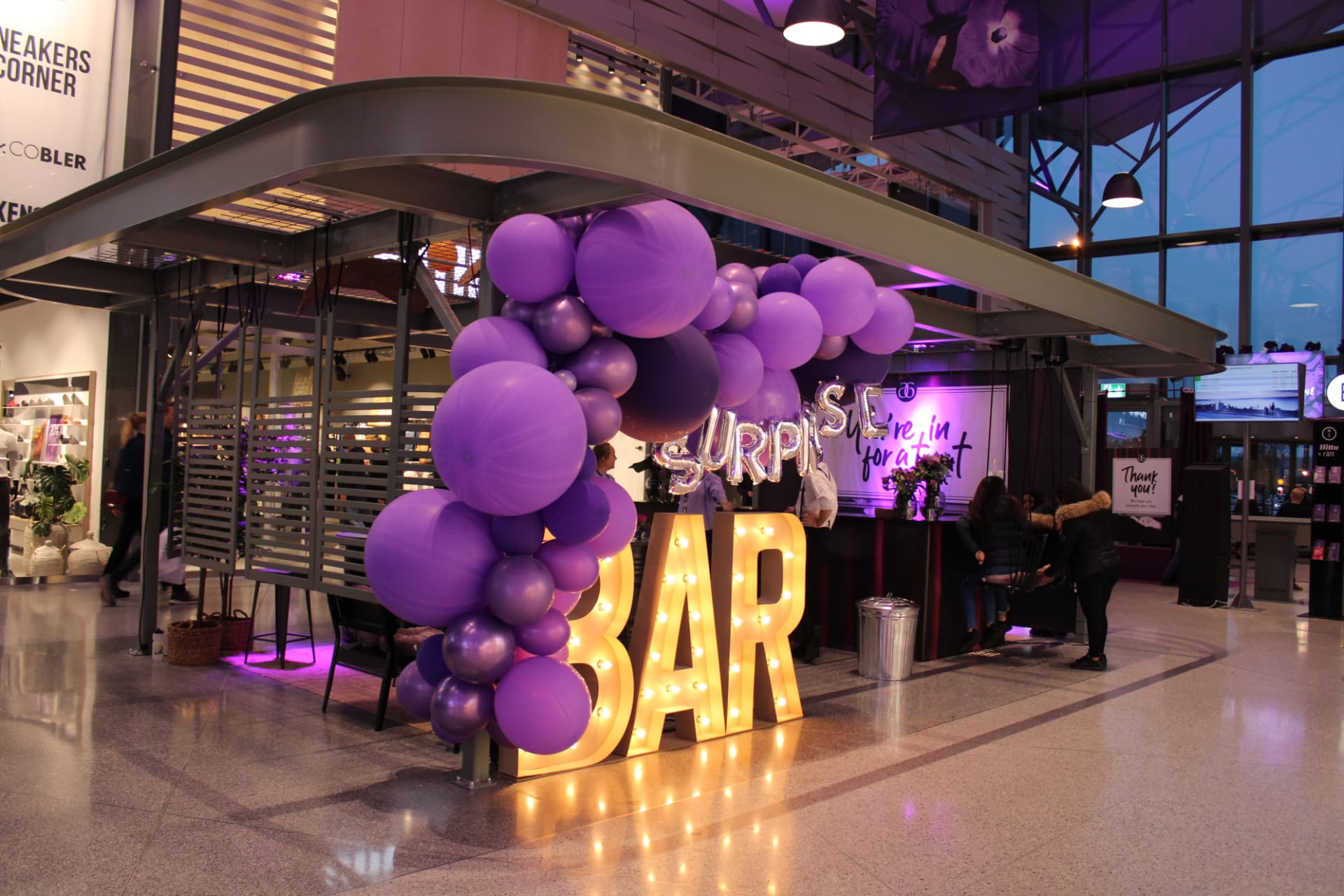 Ballongdekor i lila och upplysta BAR-bokstäver vid en eventbar